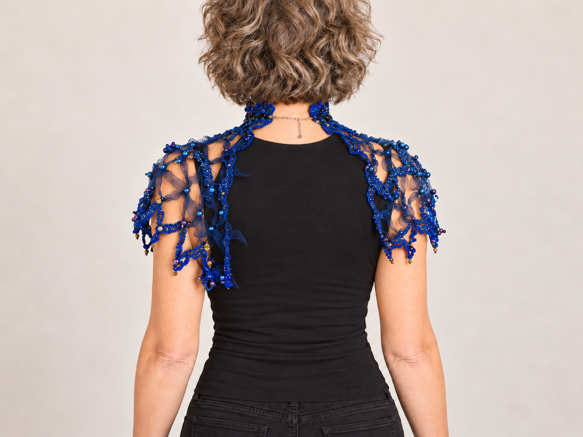 Dark blue handmade web capelet worn over a black dress – back view