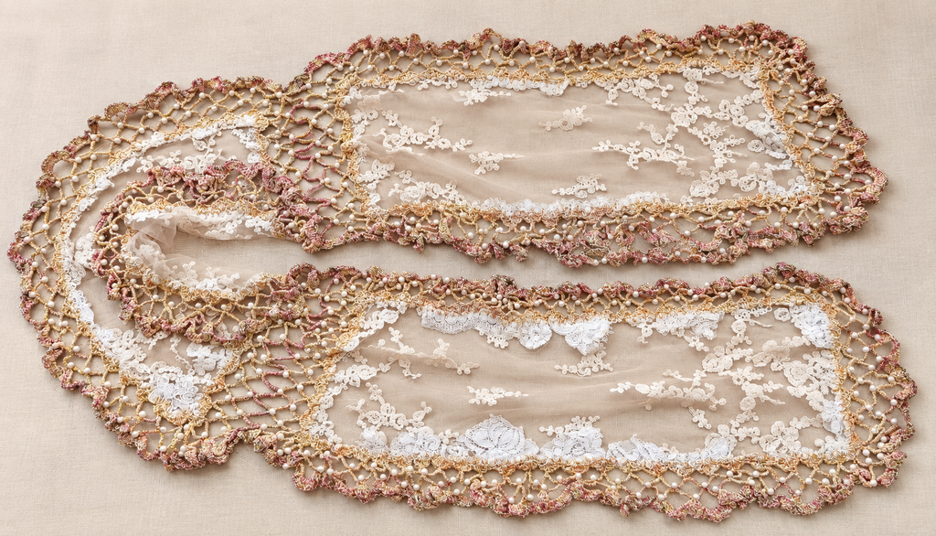 Long ecru handmade lace shawl with pearl edging laid flat