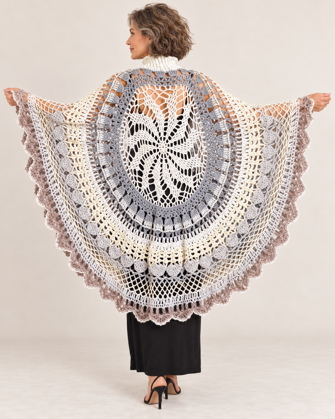 Asymmetric ecru and grey crochet poncho with turtleneck worn by a woman – back view