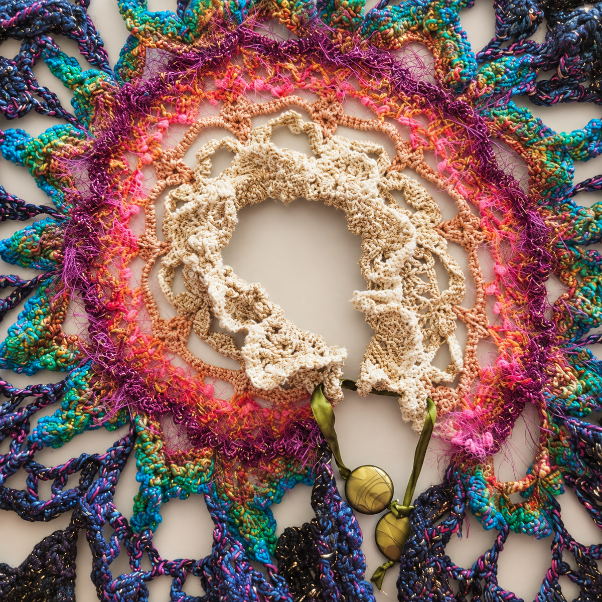 Colourful handmade crochet cape displayed flat on a light background